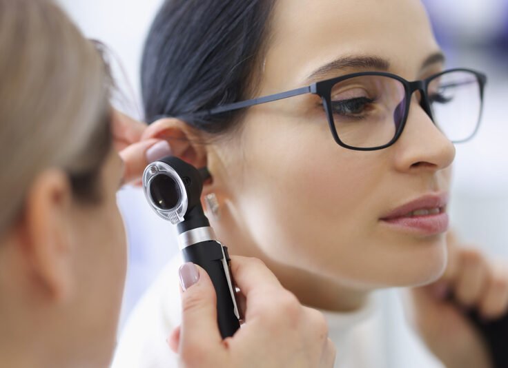 doctor-laryngologist-examining-ear-female-patient-with-glasses-using-otoscope
